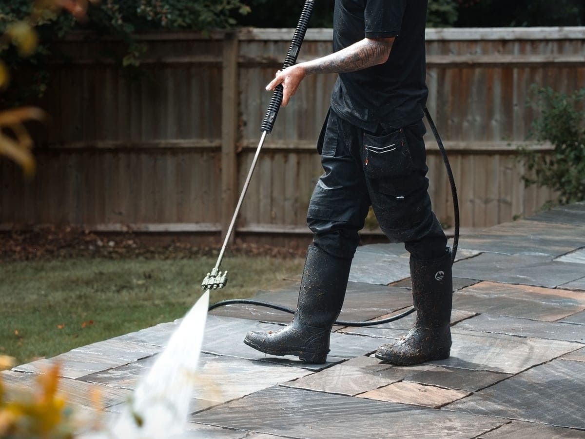 Chiltern Surface Co operative pressure washing a natural stone patio, the wet flags in the foreground